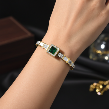 Gold cuff bangle with emerald green stone worn on wrist