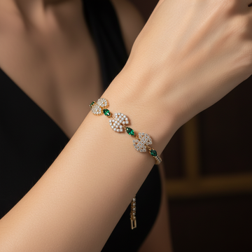 Gold crystal medallion bracelet with emerald green stones worn on wrist