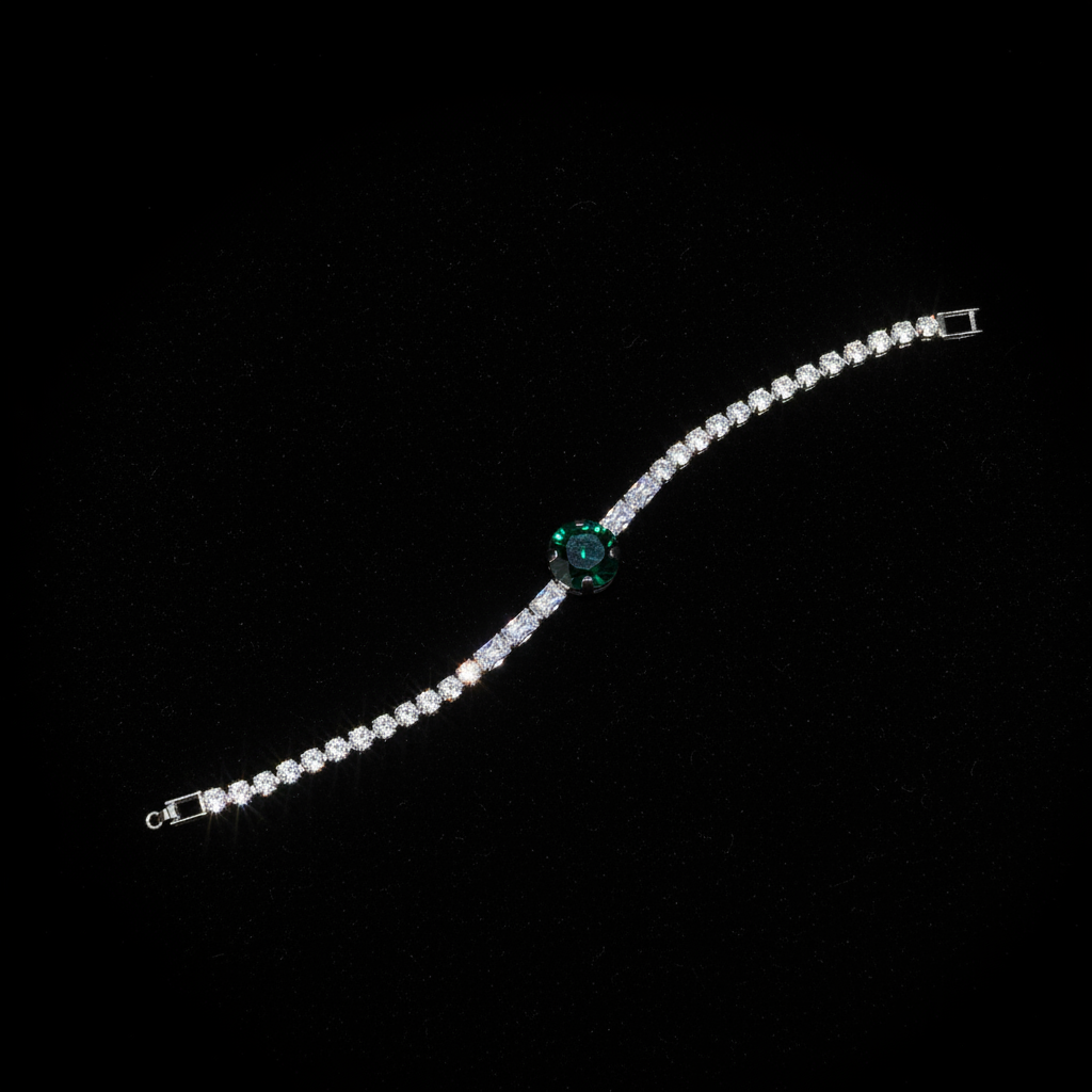 Silver crystal tennis bracelet with emerald green center stone on dark luxury background