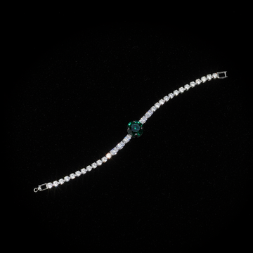 Silver crystal tennis bracelet with emerald green center stone on dark luxury background