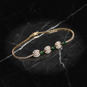 Gold crystal medallion bracelet with emerald green stones on dark luxury background