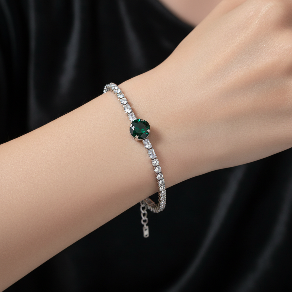 Silver crystal tennis bracelet with emerald green center stone worn on wrist