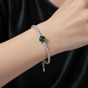 Silver crystal tennis bracelet with emerald green center stone worn on wrist